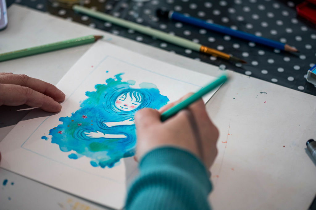 Mains en train de créer une illustration dans un univers artistique coloré