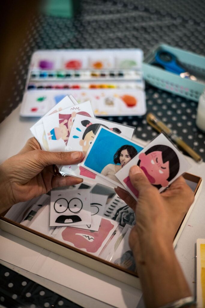 des mains qui tiennent des cartes avec des illustrations d'émotions