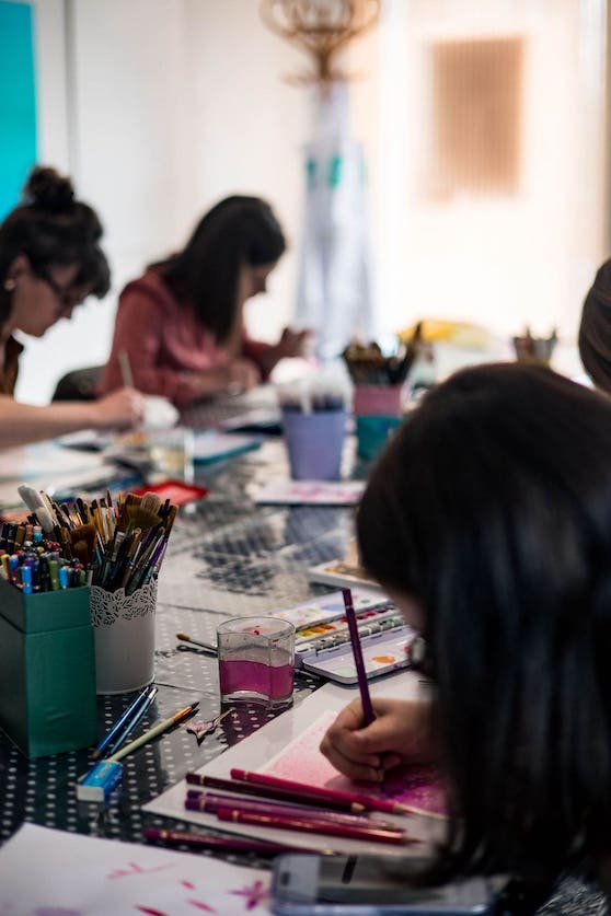 Les ateliers créatifs en groupe qui dessinent et peignent autour de la table à Mons